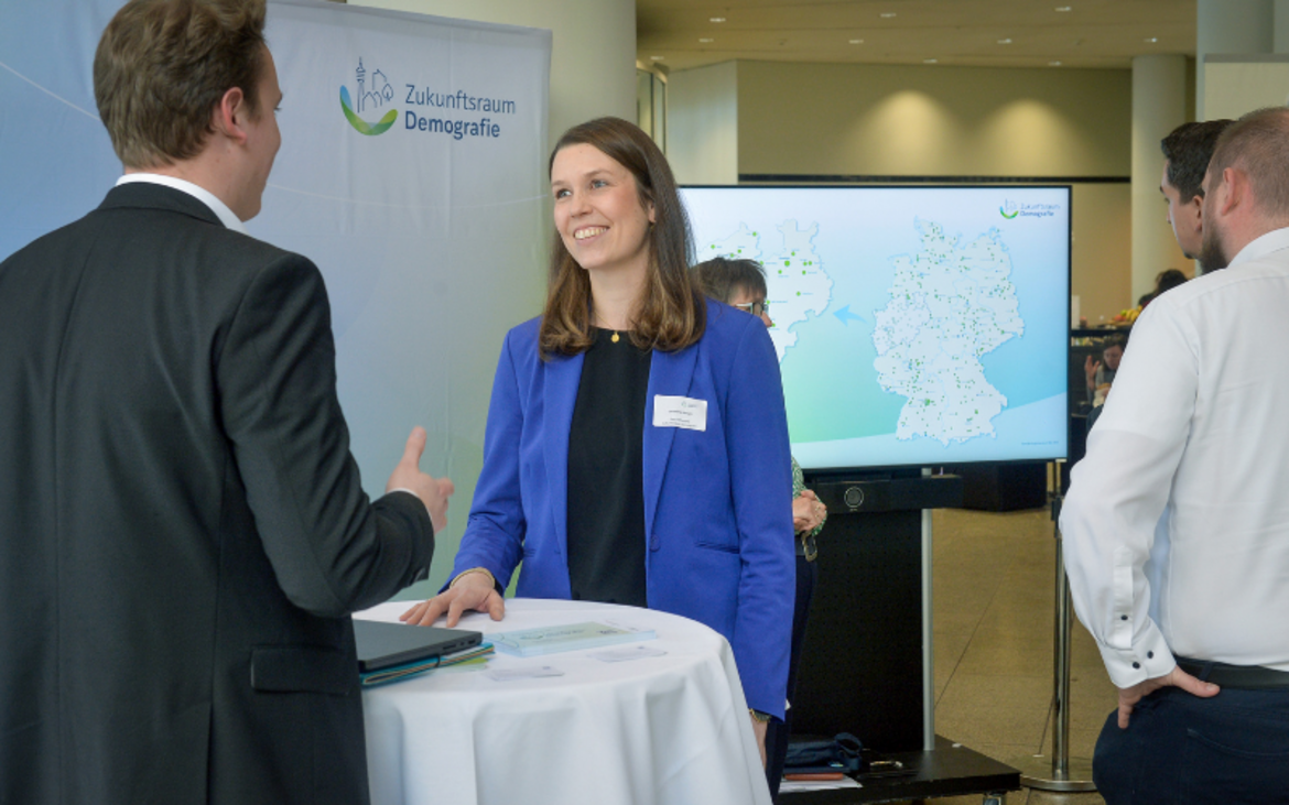 Christiane Knirsch steht am Infostand des Zukunftsraums Demografie im Landtag NRW und tauscht sich mit Landtagsabgeordneten aus.